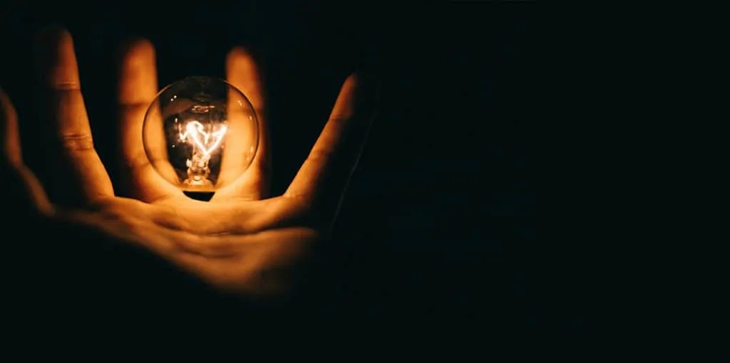Image of a hand holding a lightbulb in darkness