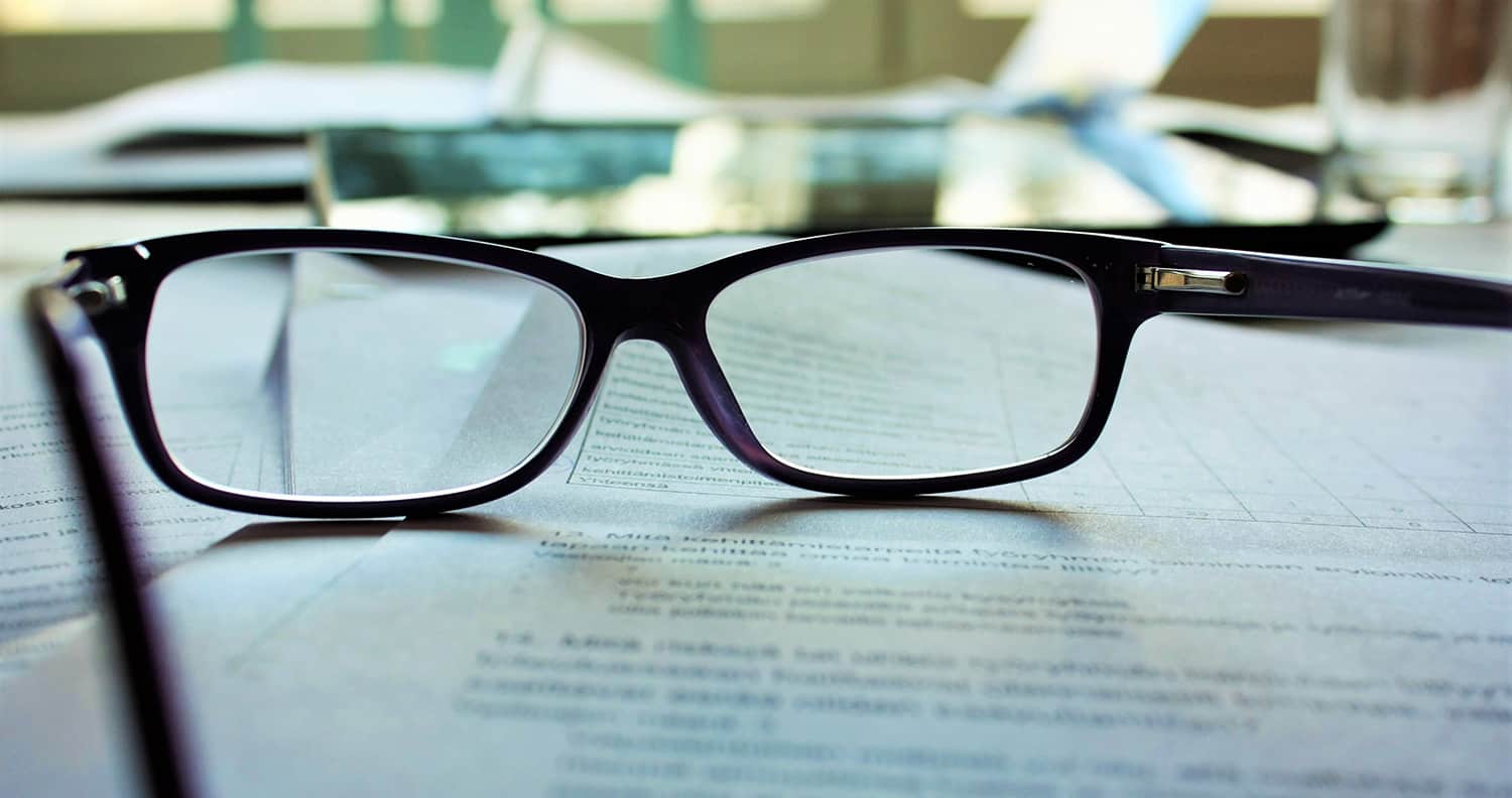 Image of glasses on a pile of paper contracts
