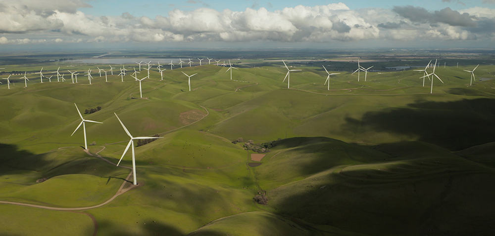 A wind turbine farm located in the mountains used to generate electricity, which is one of the many ways to conserve energy